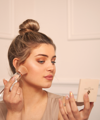 Airbrush Bronzer | Fair An open square makeup compact with a mirror on the inside of the lid and a pressed powder pan in a warm beige shade, shown on a clean white background.