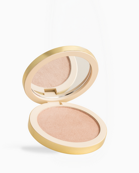 Make Me Blush | Coconut Grove An open round makeup compact with a gold-tone case, showing a shimmering light peach-beige pressed powder and a mirror on the inside of the lid, set against a clean white background.