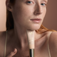 OGB Miracle Skin Tint Fair: model met rood haar houdt de skin tint vast