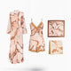 A coordinated sleepwear set displayed on a clean white background, including a long robe, a matching camisole and shorts set with lace trim, a square pillow or cushion, and a folded blanket or scarf, all in a soft peach, beige, and brown abstract print.