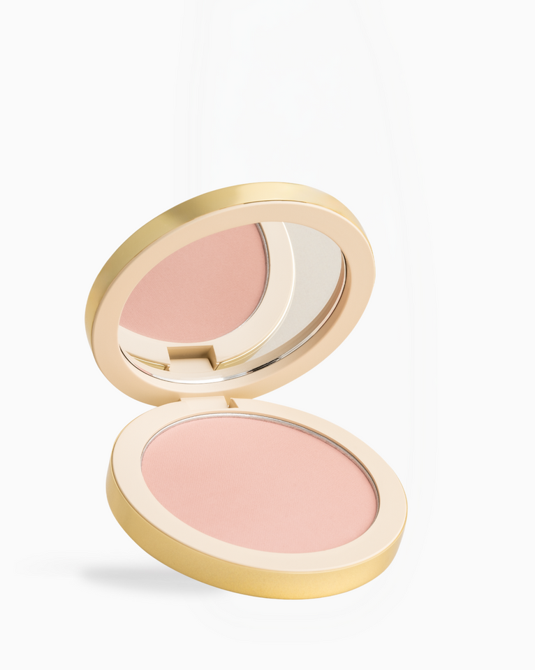 An open round makeup compact with a gold-toned case and a light pink pressed powder, shown on a clean white background.