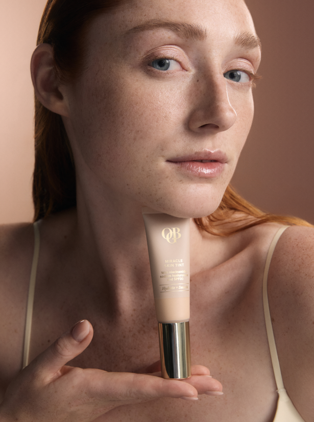 OGB Miracle Skin Tint Fair: model met rood haar houdt de skin tint vast